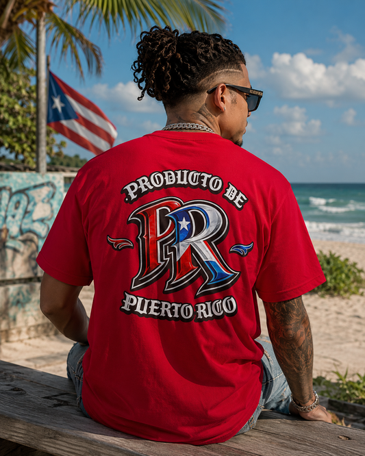 A man wearing a red graphic t-shirt with 'PRODUCTO DE PUERTO RICO' and a large 'PR' logo on the back, sitting on a wooden bench at a beach.