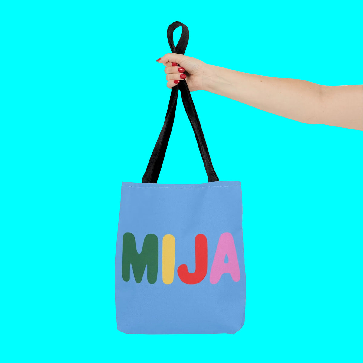 Blue tote bag with colorful letters 'MIJA' held by a hand on a white background