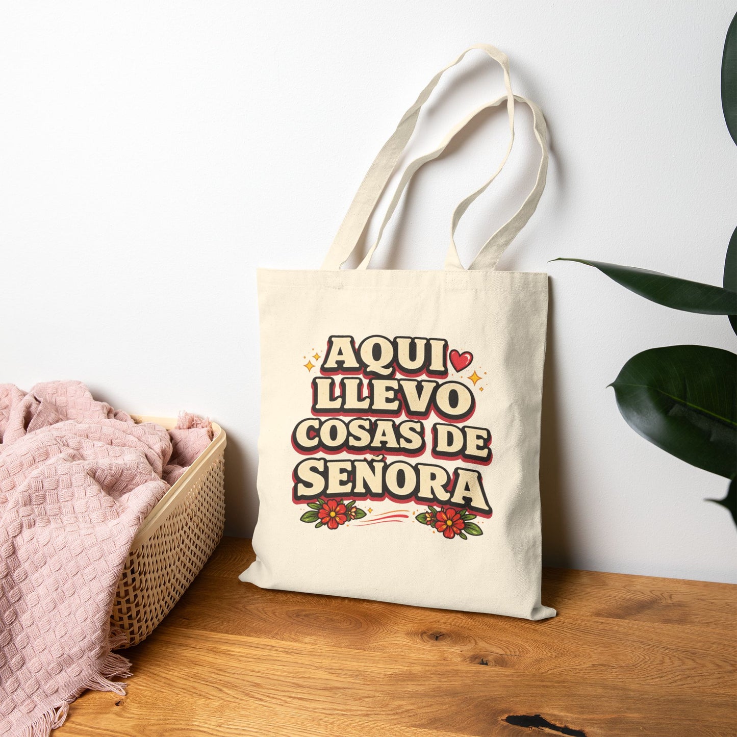 Tote bag with Spanish text on a wooden surface with a plant in the background