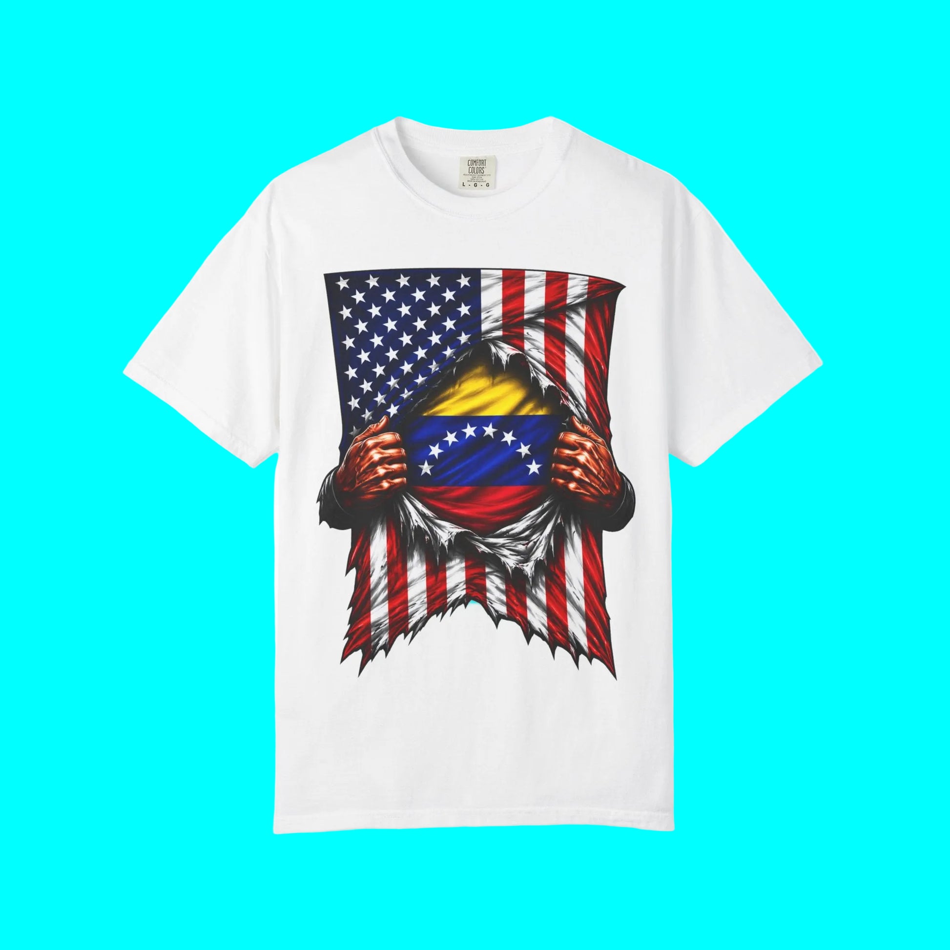 A white short-sleeve crewneck t-shirt featuring a graphic print of a patriotic ripped-tissue design. The graphic shows the American flag on the outside tearing open to reveal a yellow and blue Venezuelan flag in the center, with two red hands tearing the fabric.