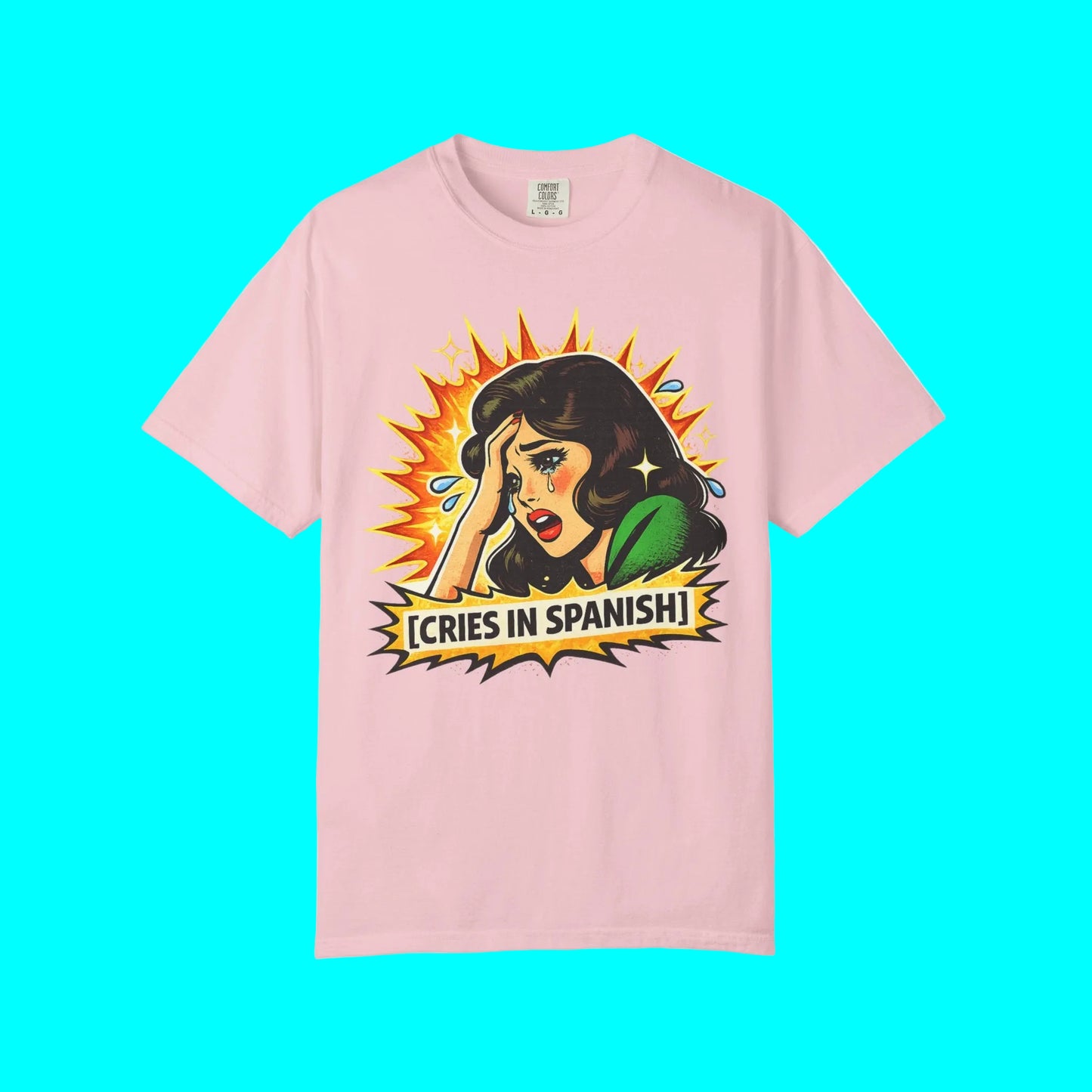 Pink t-shirt with graphic design of a woman crying and text 'Cries in Spanish' on a white background