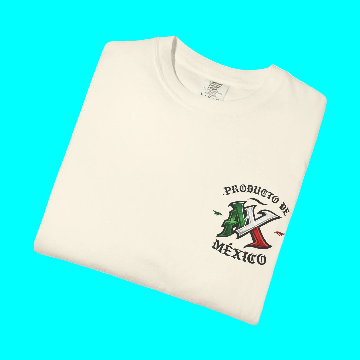A folded cream-colored t-shirt with a graphic on the left chest that reads 'PRODUCTO DE MÉXICO' with a stylized Mexican flag and mountain design, shown on a plain white background.