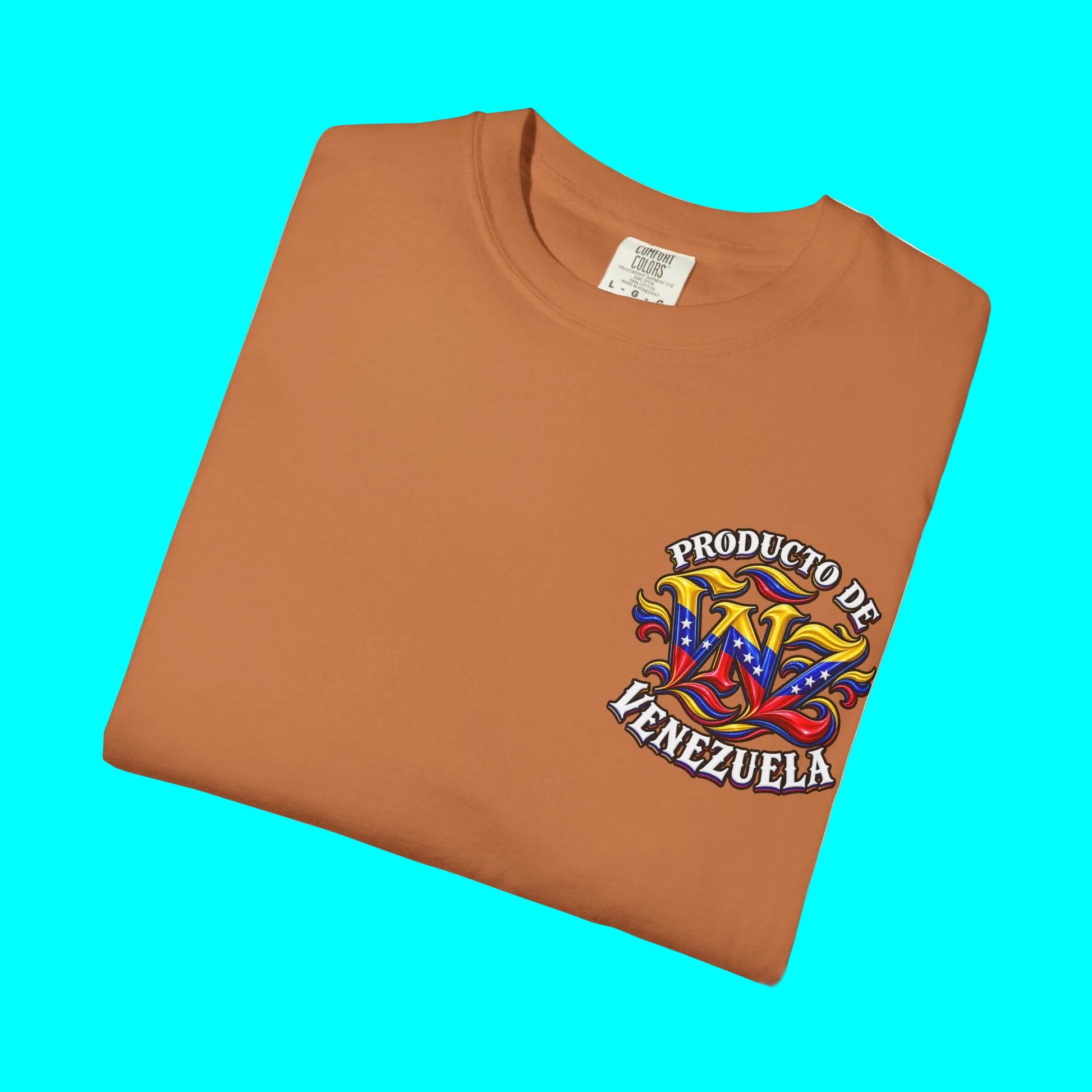A folded orange crewneck t-shirt with a colorful graphic on the left chest that reads 'PRODUCTO DE HENEZUELA' with a stylized 'HW' in the Venezuelan flag colors, shown on a white background.