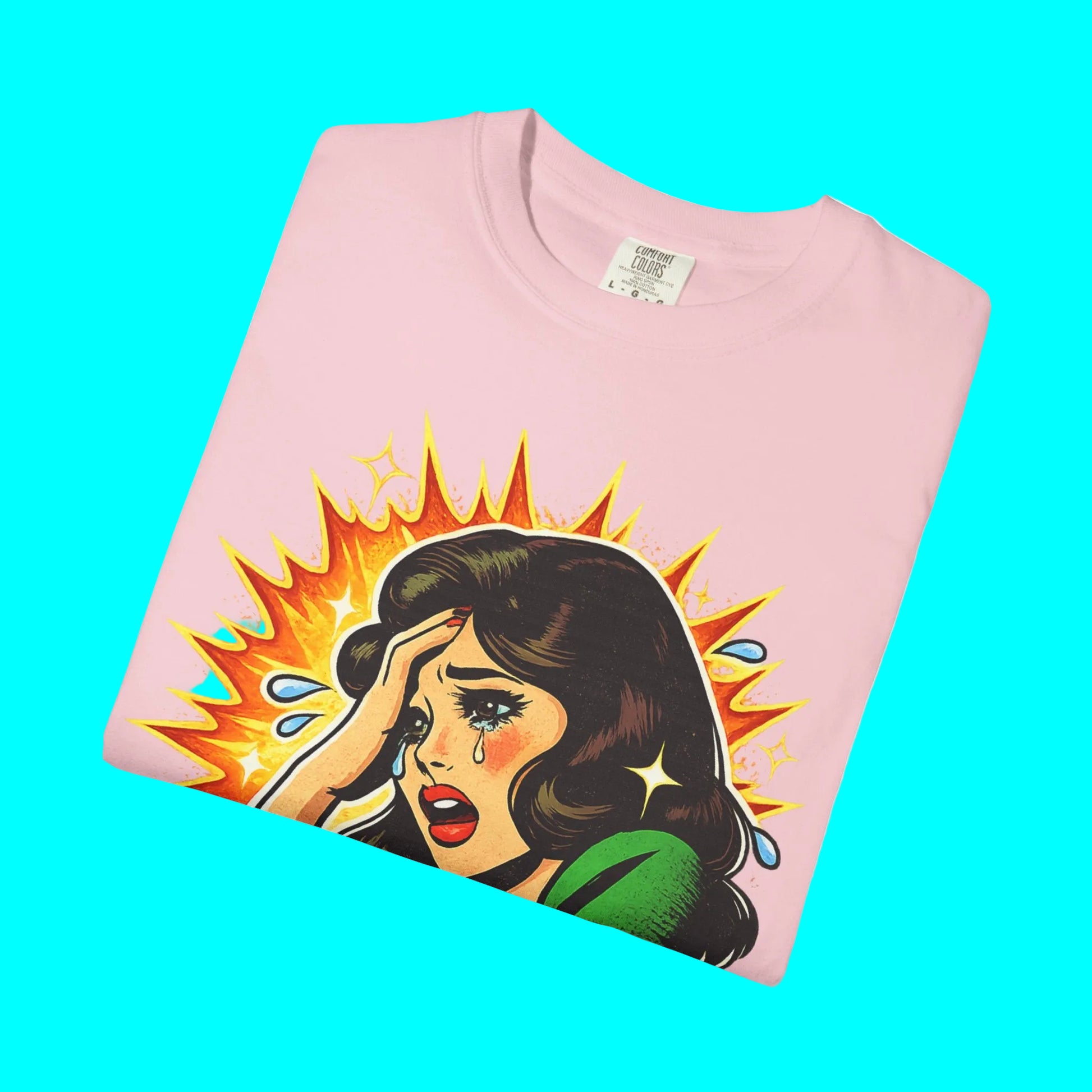 Folded pink t-shirt with a graphic of a woman with an explosion background on a white background