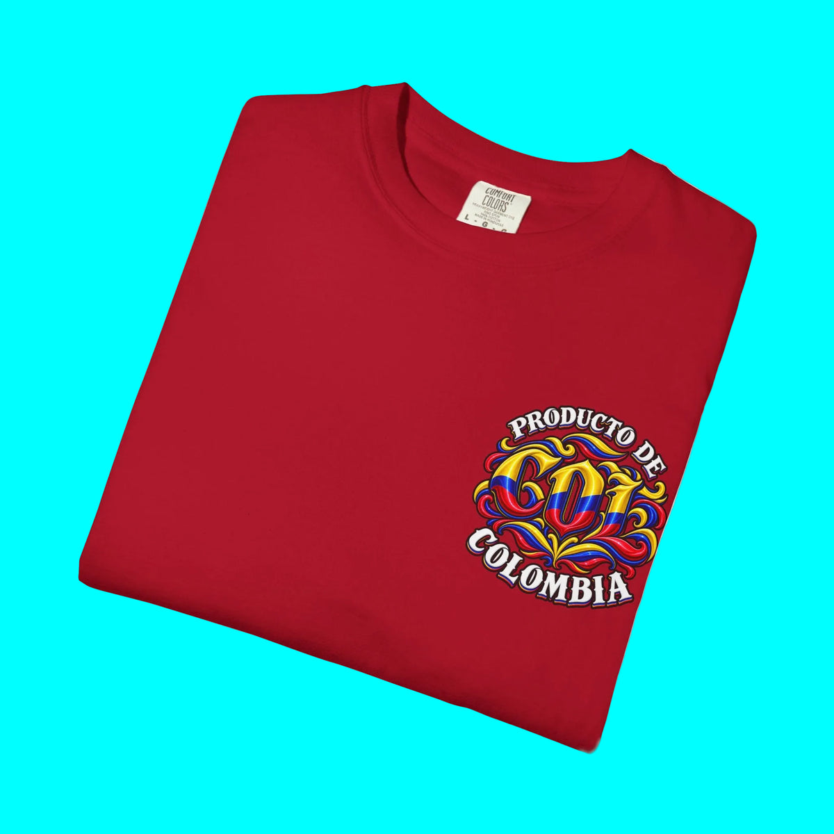 A folded red t-shirt with a colorful graphic on the left chest that reads 'PRODUCTO DE COLOMBIA' in white, yellow, blue, and red. The shirt is photographed on a clean white background.