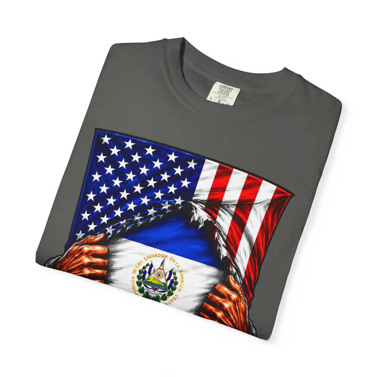A dark gray folded t-shirt featuring a graphic print of the United States flag tearing open to reveal the flag of El Salvador underneath, with stylized hands pulling the fabric apart.