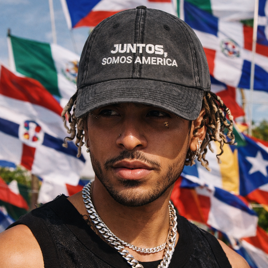 Man wearing a cap with 'Juntos, Somos America' text in front of flags