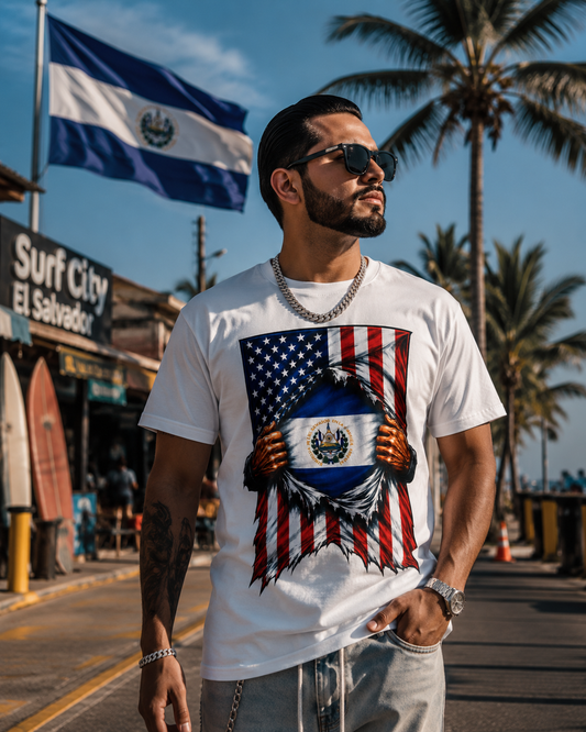 A man wearing a white graphic t-shirt with a patriotic design of the Salvadoran flag and eagle, standing on a sunny beach street with palm trees and a Nicaraguan flag in the background.