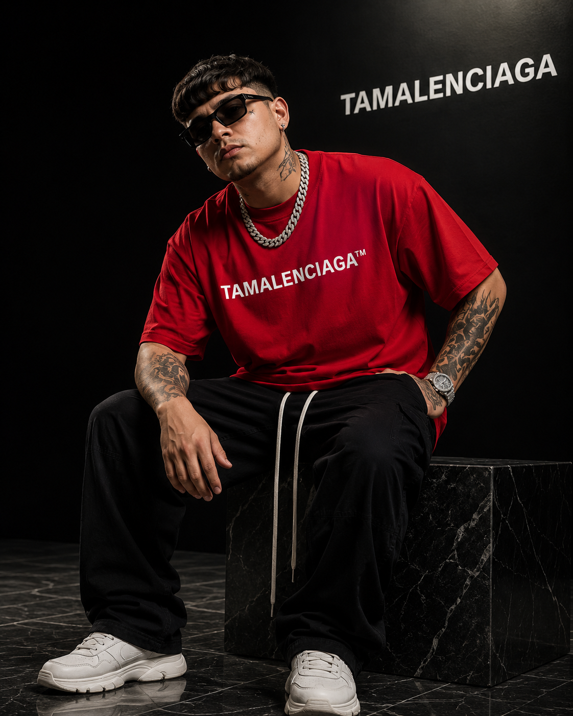 Person wearing a red 'TAMALENCIAGA' t-shirt sitting on a black surface with 'TAMALENCIAGA' branding in the background.
