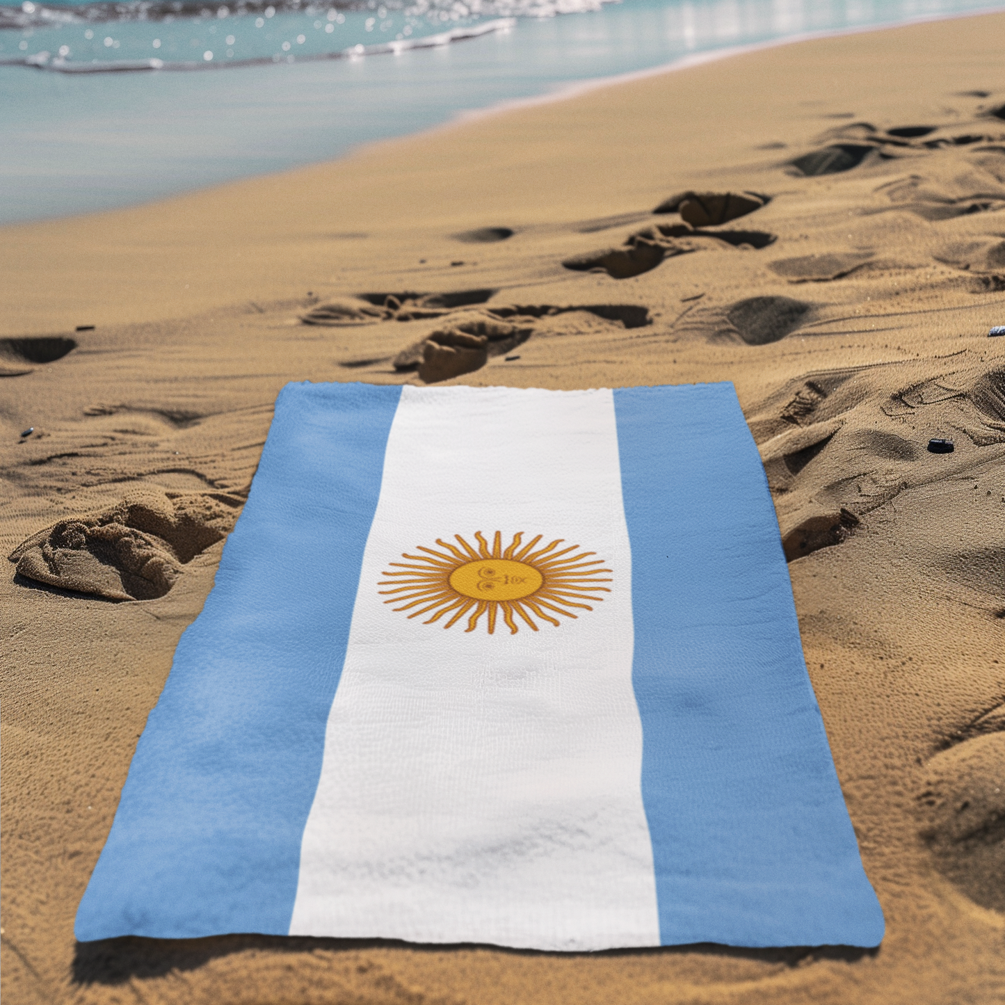 Argentine flag towel on a sandy beach with ocean in the background