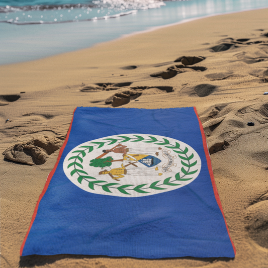 Blue towel with a white emblem on a sandy beach with ocean waves in the background